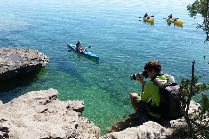 a group of people on a rock next to a body of water