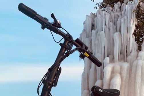 handlebars show the brake and bell set up of an ebike