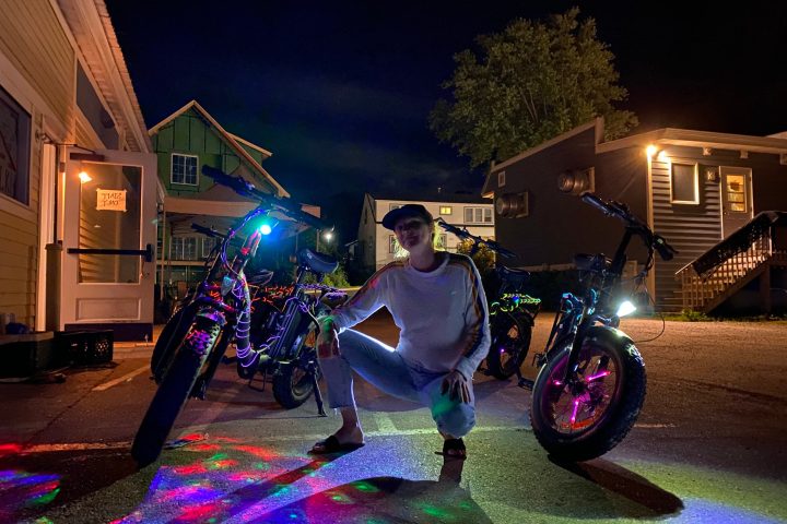A man squats in front of bikes glowing with lights